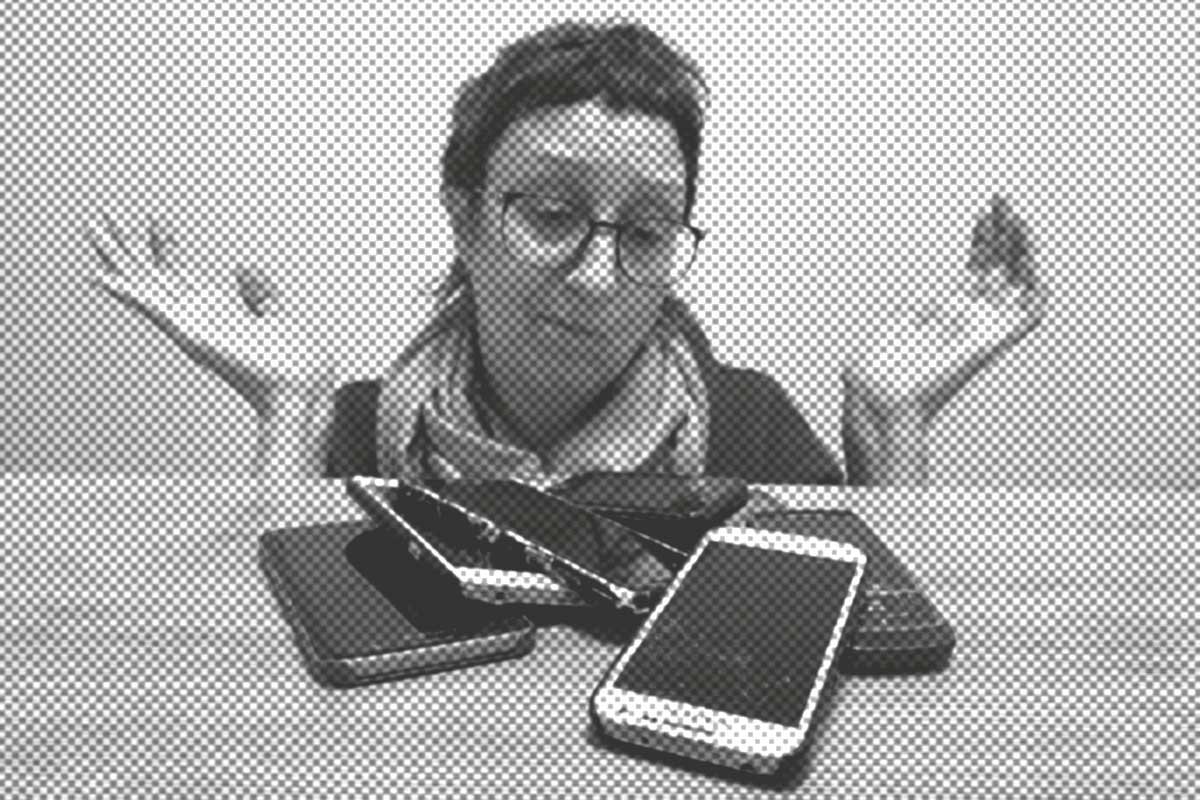 Eine Person mit Brille und Schal zuckt hinter einem mit mehreren Smartphones übersäten Tisch mit den Schultern. Das Bild ist schwarz-weiß mit einem Punktmustereffekt.