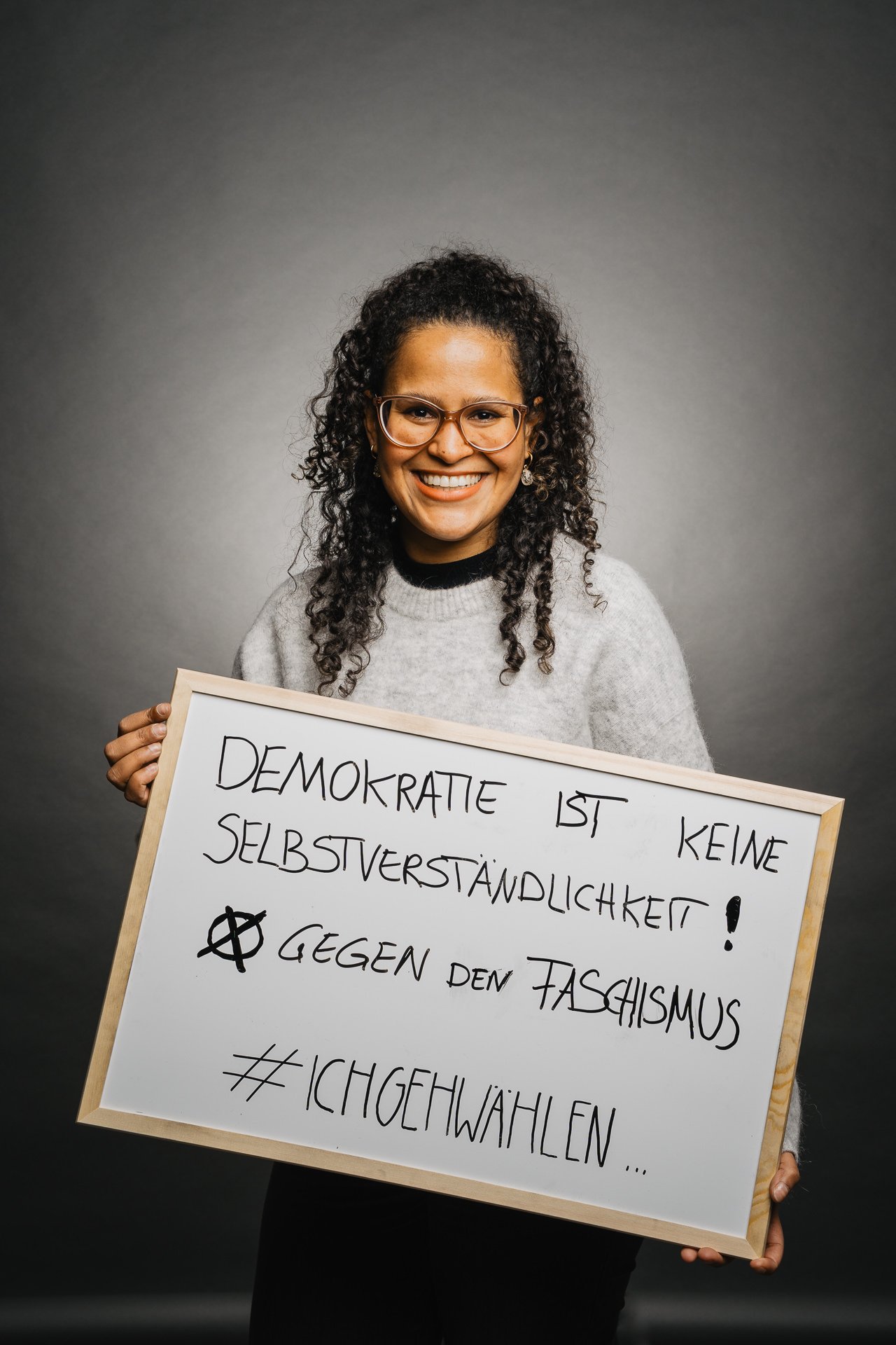 Eine Person hält ein Schild mit der Aufschrift „Demokratie ist nicht selbstverständlich! Gegen Faschismus. #IchWähle.“.