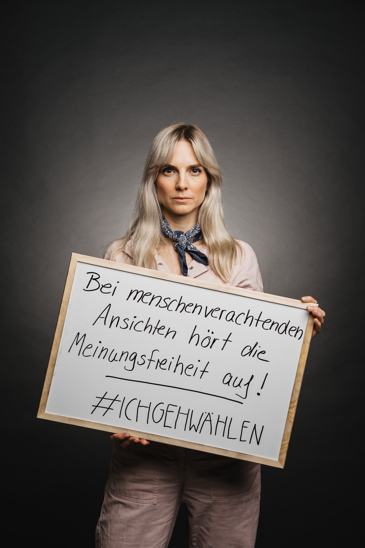 Person, die ein Schild mit handgeschriebenem deutschem Text hält, der sich gegen entmenschlichende Ansichten ausspricht und zur Stimmabgabe aufruft.