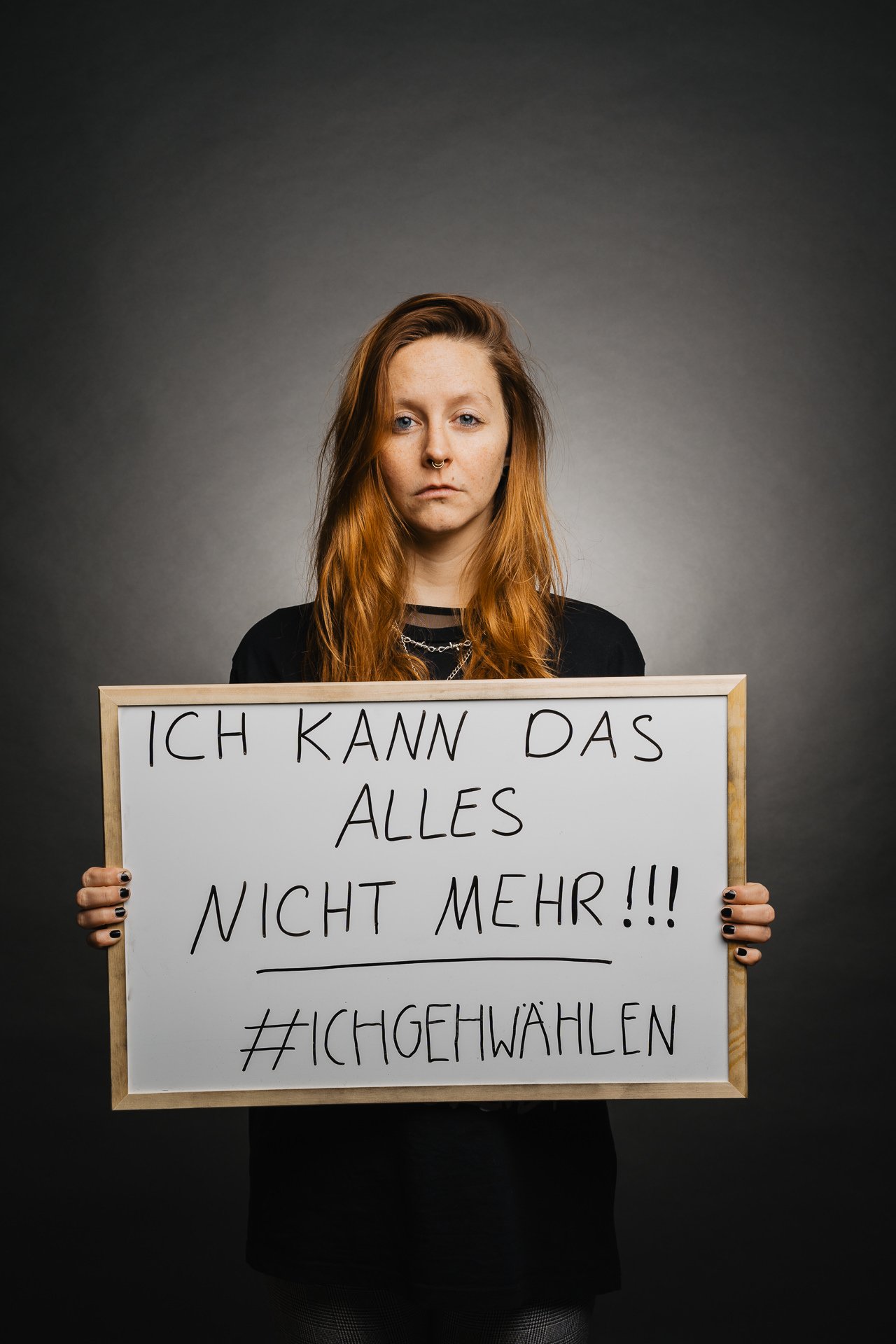 Person hält ein Schild mit handgeschriebenem deutschen Text: „Ich kann das alles nicht mehr!!! #ichgehwählen“ vor dunklem Hintergrund.