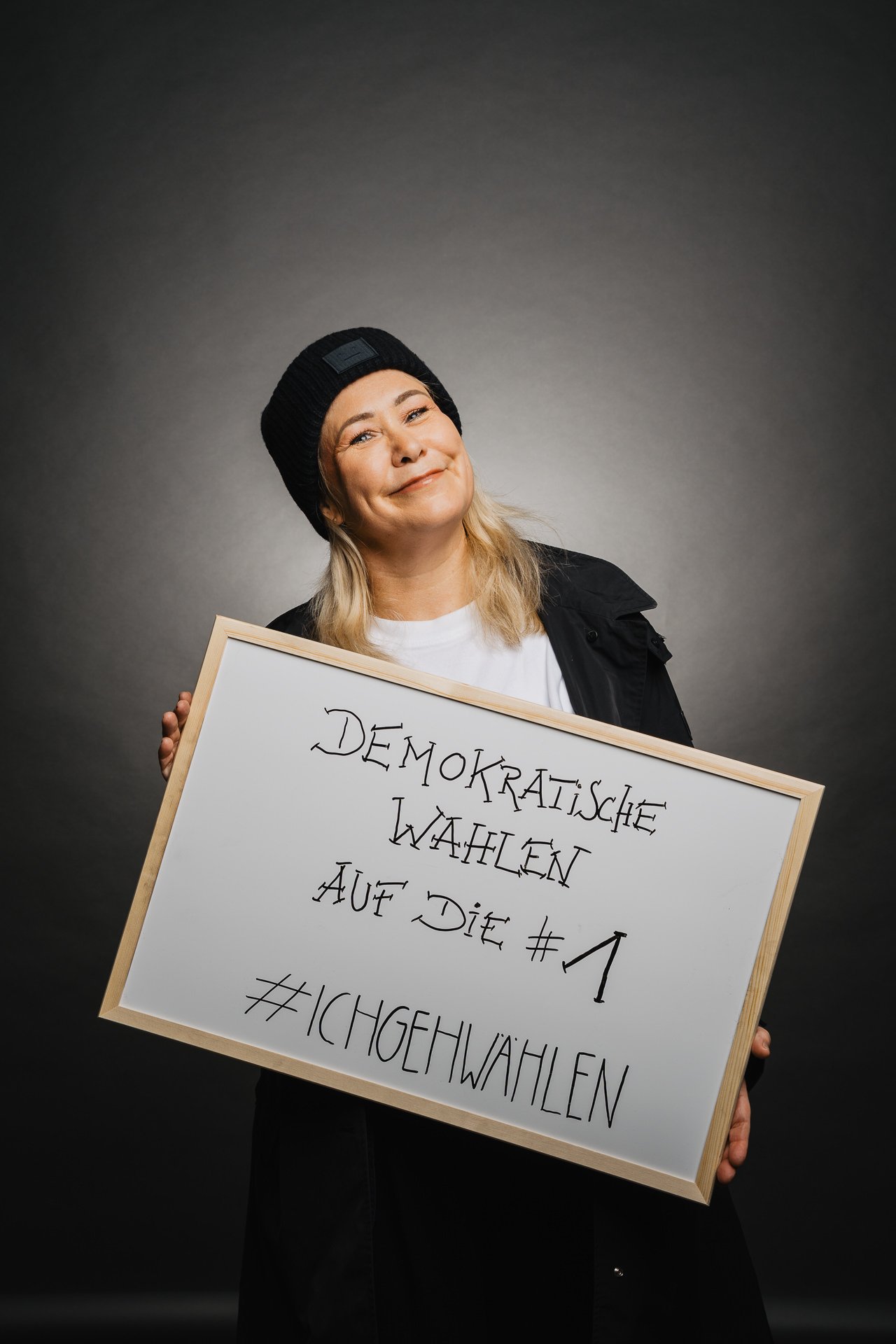 Eine Person mit schwarzem Hut hält ein Schild mit der deutschen Aufschrift „#IchGehWählen“.